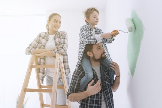 Ein Bild einer Familie, die eine Wand streicht.